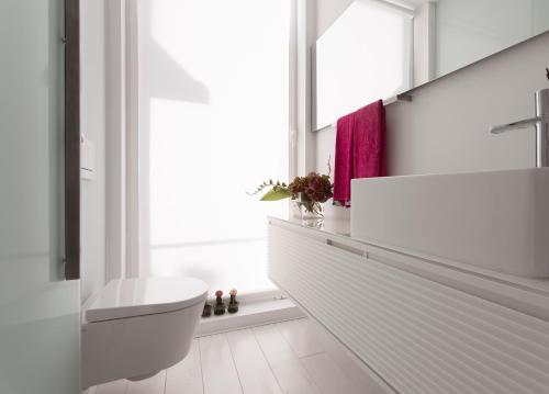 a white bathroom with a sink and a toilet at M Costa Nova in Costa Nova