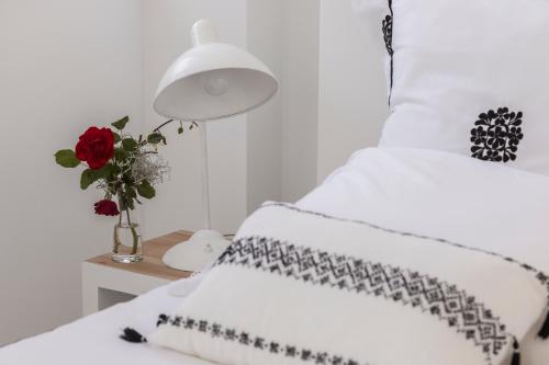 a bedroom with two white beds and a vase of flowers at M Costa Nova in Costa Nova