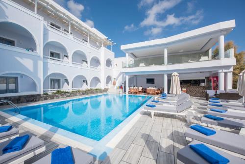 a villa with a swimming pool and lounge chairs at Blue Waves Suites & Apartments in Kamari