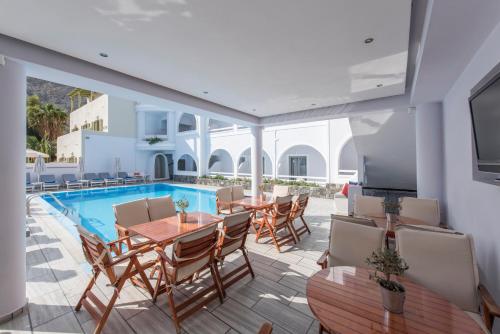 a patio with a table and chairs and a swimming pool at Blue Waves Suites & Apartments in Kamari
