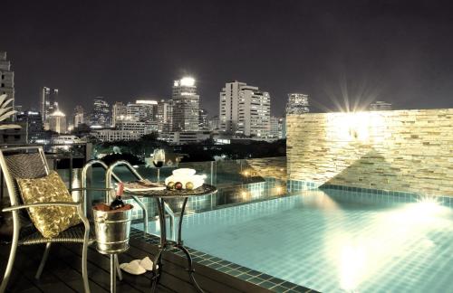 バンコクにあるRongratana Executive Residence Bangkokの夜は街のスカイラインを望む屋上スイミングプールを利用できます。