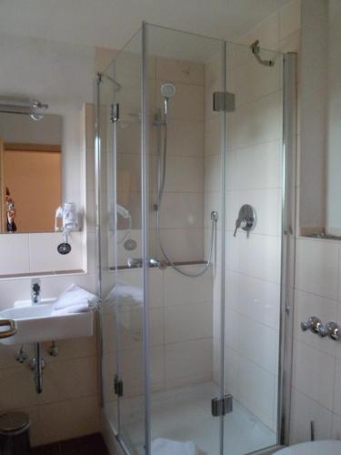 a shower with a glass door next to a sink at Berggasthaus Kraxenberger in Brannenburg