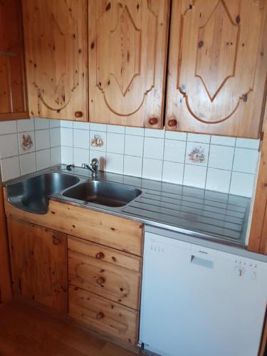 - une cuisine avec un évier en acier inoxydable et des placards en bois dans l'établissement Nybu Two-bedroom cottage, à Geilo
