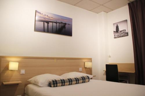 a hotel room with a bed and a desk at Hôtel Vol de Nuit Purpan in Toulouse