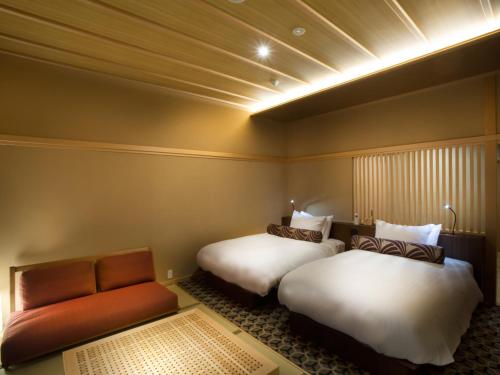 a hotel room with two beds and a couch at Saka Hotel Kyoto in Kyoto