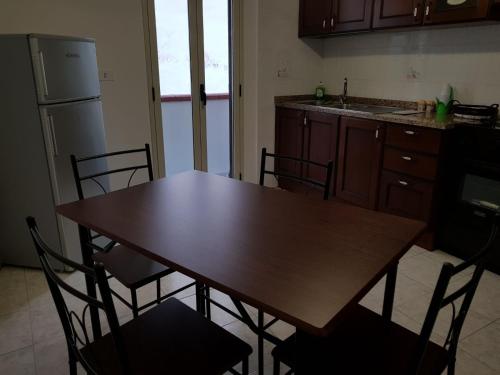 cocina con mesa, sillas y nevera en XXI Agosto Home, en Reggio Calabria