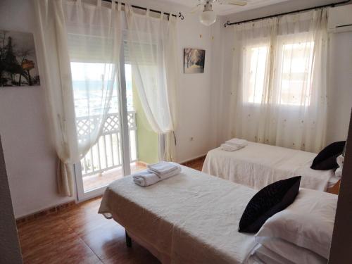 a bedroom with two beds and a window with a balcony at Los Miradores in La Manga del Mar Menor