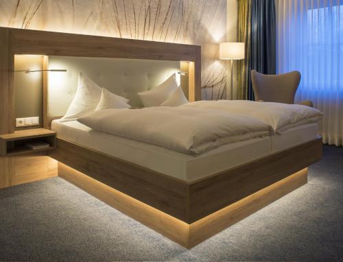 a bedroom with a large bed with a wooden headboard at IDINGSHOF Hotel & Restaurant in Bramsche