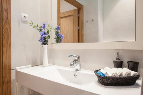 a bathroom with a sink with a vase of flowers at BCNGOTIC 22 in Barcelona
