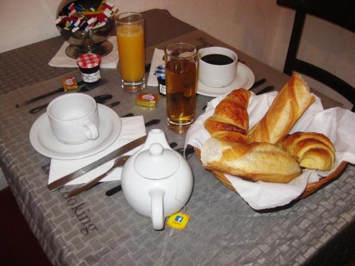 a table with a breakfast of croissants and coffee and drinks at Hôtel du Pont Neuf in Paris