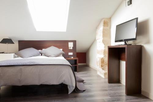 a bedroom with a bed with a flat screen tv at Apartamentos Sol de Mayo in Úbeda