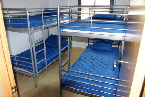 a room with three bunk beds with blue sheets at Goldhome - Cristallmar in Empuriabrava