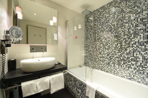 a bathroom with a sink and a tub and a mirror at Mercure Dijon Centre Clemenceau in Dijon