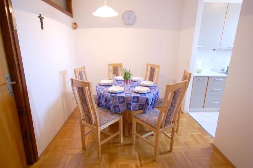 a dining room with a table and chairs and a clock at Mezlar Apartment by El-pi Tours in Njivice