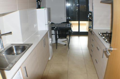 a kitchen with a sink and a refrigerator and a table at Goldhome - Cristallmar in Empuriabrava