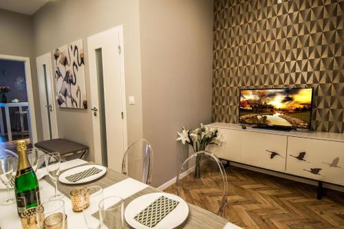 een eetkamer met een tafel en een tv bij Executive Bright Apt. by Ruterra in Praag