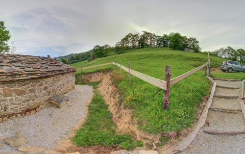 a grassy hill with a fence and a car on it at Cabañas con Encanto in San Roque de Ríomiera