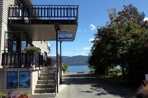 a building with a balcony next to a lake at Edgewater Motel in Te Anau