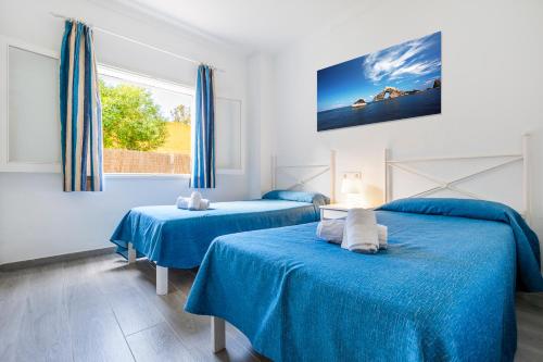 two beds in a room with blue sheets at Apartamentos Don Miguel in Port de Pollensa