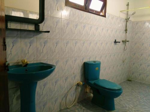 a bathroom with a blue toilet and a sink at Sunnys Beach Guest House in Hikkaduwa