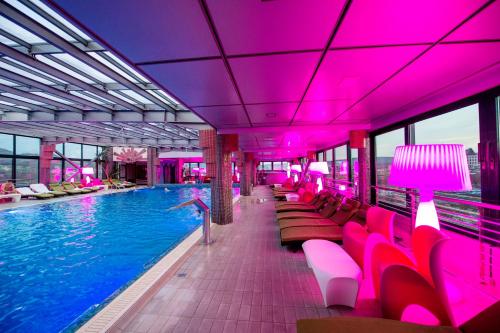 a swimming pool with pink lighting in a building at Business Hotel Conference Center & Spa in Târgu-Mureş