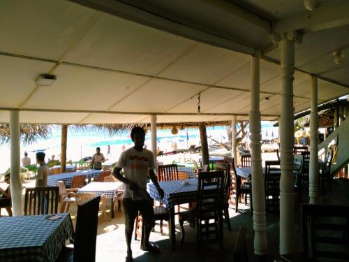 a man walking through a restaurant with tables and chairs at Sunnys Beach Guest House in Hikkaduwa