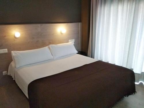 una camera da letto con un letto grande con cuscini bianchi di Hotel Delicias a Saragozza