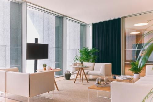 a living room with white chairs and a flat screen tv at Melia Palma Bay in Palma de Mallorca