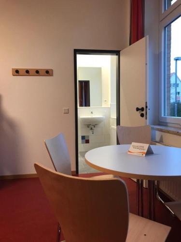 a room with a table and chairs and a mirror at Jugendherberge Heide in Heide