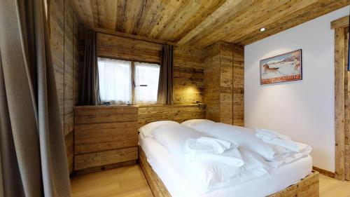 a bedroom with a bed and a wooden wall at Tass 3 in Silvaplana