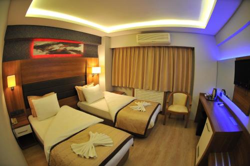 a hotel room with two beds and a television at Hotel Kabacam in İzmir