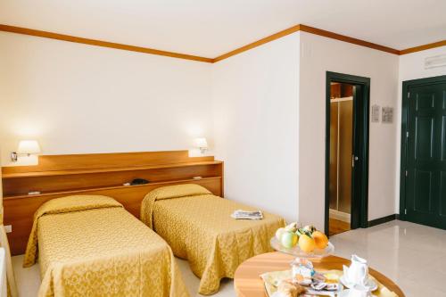 a room with two beds and a table with a bowl of fruit at Hotel Residence Federiciano in Valenzano