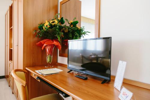a computer monitor on a desk with a vase of flowers at Hotel Residence Federiciano in Valenzano
