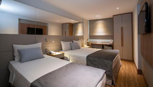 a hotel room with two beds and a television at Hotel Atlântico Travel Copacabana in Rio de Janeiro