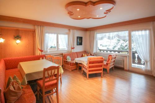 a dining room with a table and chairs and windows at Apartments- und Ferienhaus Anton in Garmisch-Partenkirchen