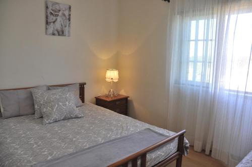 1 dormitorio con 1 cama con lámpara y ventana en Casa Serra e Mar, en Mafra