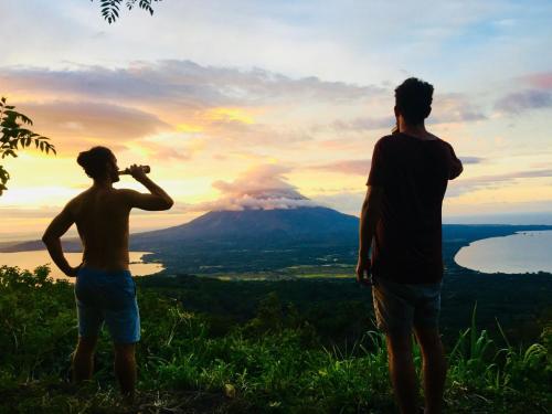 two men standing on a hill looking at a mountain at Hospedaje Bananas in Altagracia