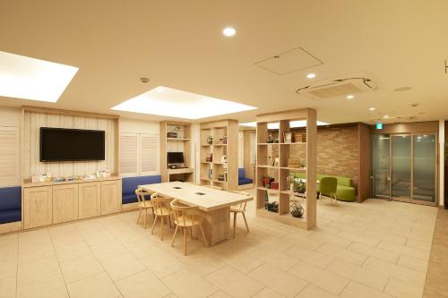 a room with a table and chairs and a tv at Sotetsu Fresa Inn Ginza Sanchome in Tokyo