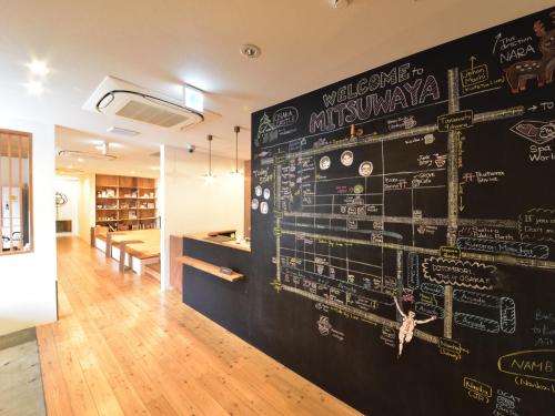 a black wall with a wall of drawings on it at Hostel Mitsuwaya Osaka in Osaka