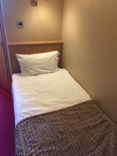 a bed with white sheets and pillows in a room at Crescent Hotel in Reading