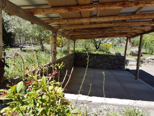 a wooden pergola with a stone wall in a yard at Posta Nehuen Cabañas in Potrerillos