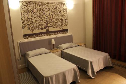 pokój hotelowy z 2 łóżkami i obrazem na ścianie w obiekcie Ursino rooms apartment w Katanii