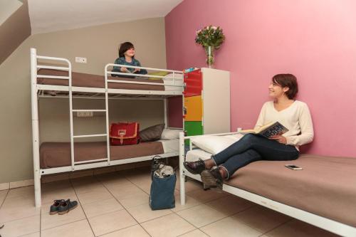 a woman sitting on a bed in a room with bunk beds at Le Montclair Montmartre by River in Paris
