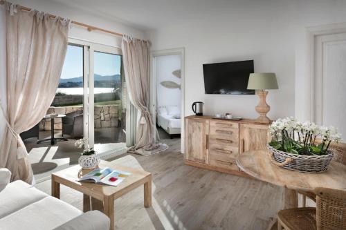 a living room with a couch and a tv at Gabbiano Azzurro Hotel & Suites in Golfo Aranci