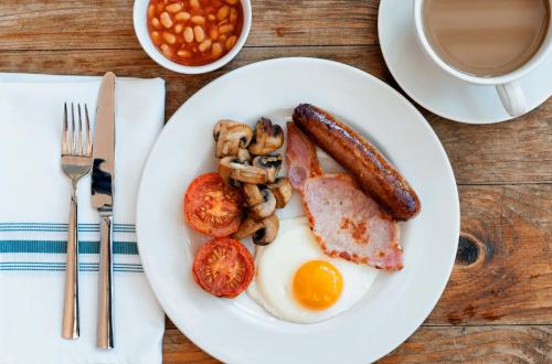 un plato de desayuno con huevos, salchichas, setas y frijoles en The Coach House, en Derby