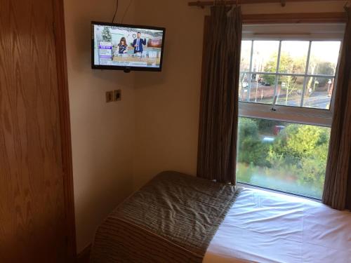 a bedroom with a bed and a tv and a window at Crescent Hotel in Reading