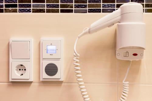 a white hairdryer on a wall next to two appliances at Pension Anna in Mondsee