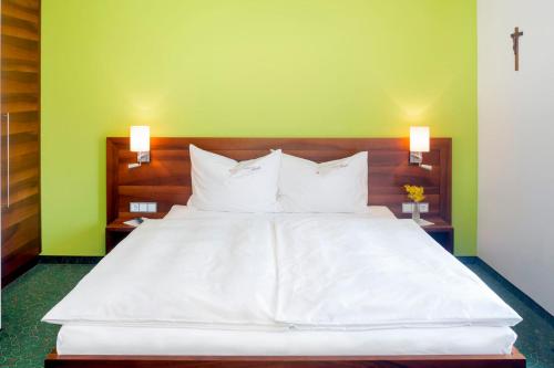 a large white bed in a room with green walls at Pension Anna in Mondsee