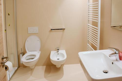 La salle de bains blanche est pourvue de toilettes et d'un lavabo. dans l'établissement Casa Baldelli, à Dobbiaco