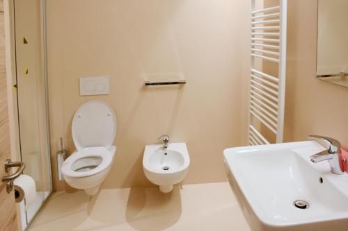 a white bathroom with a toilet and a sink at Casa Baldelli in Dobbiaco